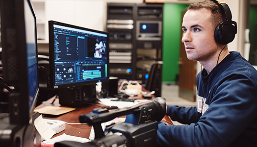 A young man working on his computer in an editing bay