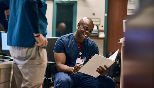 A health professional going through a file and talking to a colleague standing next to him.