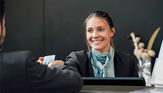 A hotel hostess is handing out a key card to a customer.