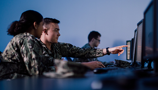 A group of military service members working on their computers in a room