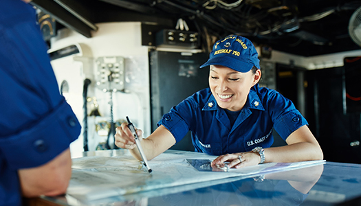 Two Coast Guard personnel looking over a map in an operations room.