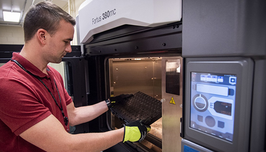 A technician wearing protective gloves working on a machine.