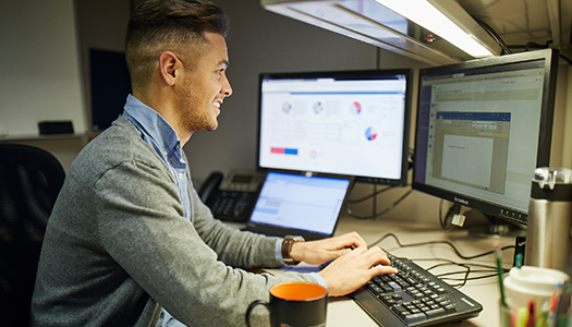 A man seated at his desk working on his computer